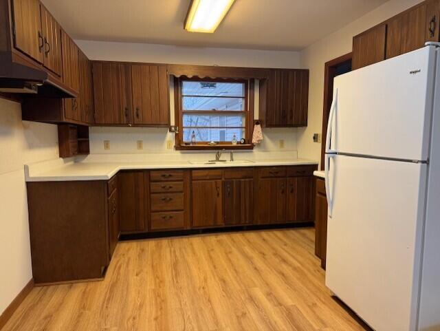 kitchen with a sink, light wood-style floors, light countertops, and freestanding refrigerator