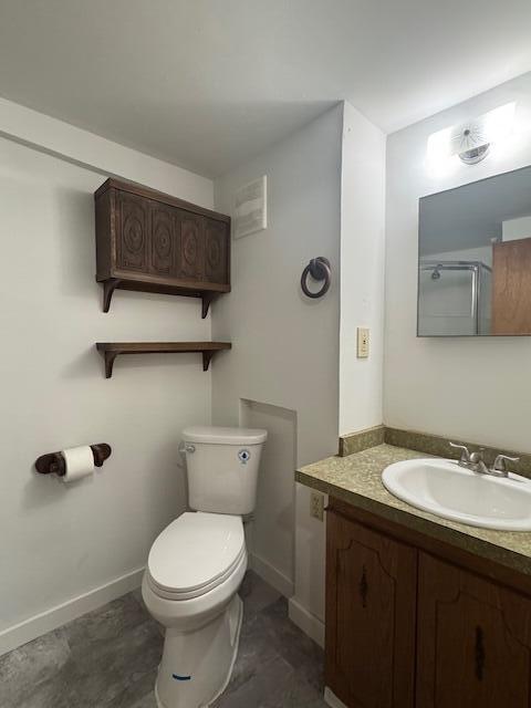 bathroom featuring a shower, baseboards, toilet, and vanity