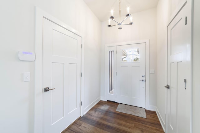 foyer featuring a chandelier, dark wood finished floors, and baseboards