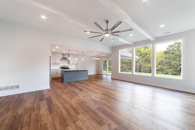 unfurnished living room featuring baseboards, visible vents, dark wood finished floors, a ceiling fan, and beamed ceiling