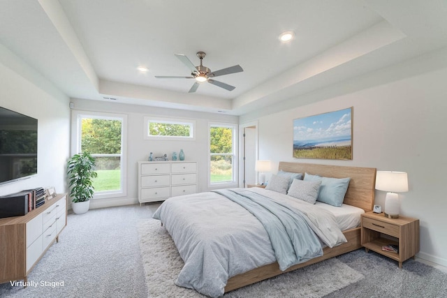 bedroom featuring a tray ceiling, visible vents, light carpet, ceiling fan, and baseboards