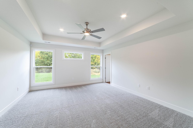 empty room with a tray ceiling, recessed lighting, carpet flooring, ceiling fan, and baseboards