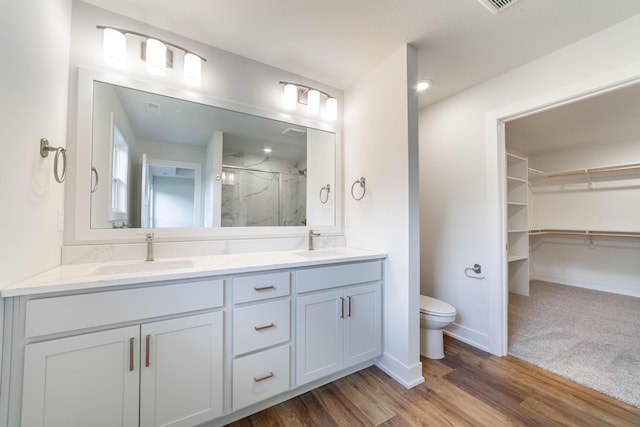 full bathroom featuring toilet, a sink, a marble finish shower, and double vanity