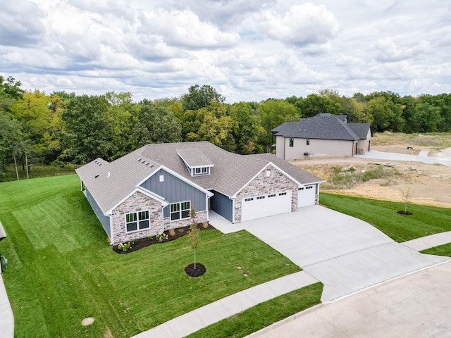 view of front of house with concrete driveway, an attached garage, board and batten siding, a front yard, and stone siding