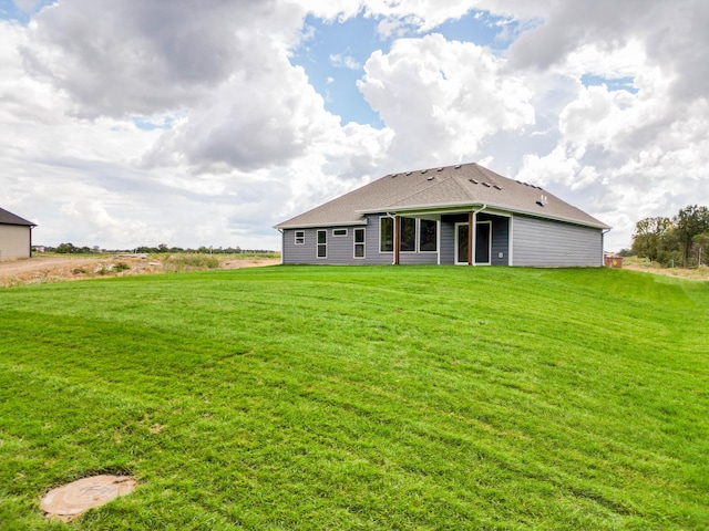 back of property featuring a yard and roof with shingles