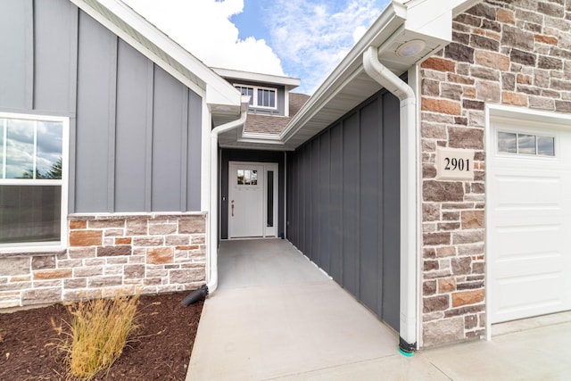 property entrance featuring stone siding, board and batten siding, and an attached garage