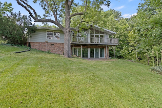 rear view of house featuring a wooden deck, a lawn, and brick siding