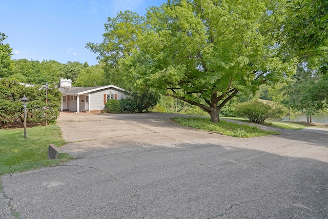 view of front of property featuring a front yard, concrete driveway, and a chimney