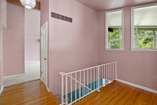 corridor featuring baseboards, visible vents, and wood finished floors