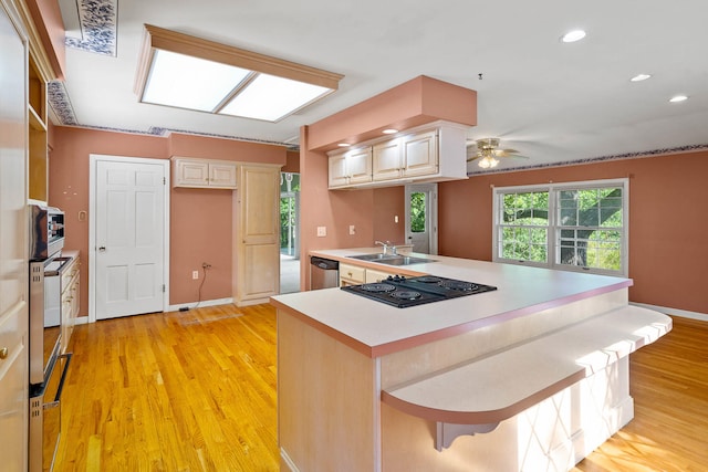 kitchen with light wood finished floors, baseboards, a peninsula, stainless steel appliances, and light countertops