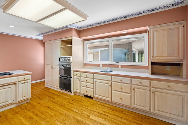 kitchen with light wood finished floors, light brown cabinets, visible vents, and a sink