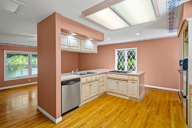 kitchen with light wood finished floors, a peninsula, light countertops, stainless steel dishwasher, and a sink