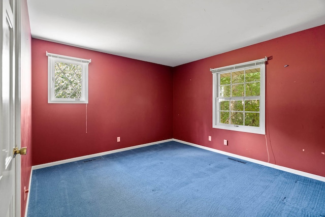 spare room with carpet floors, visible vents, and baseboards