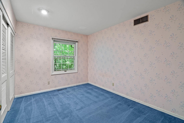 unfurnished bedroom featuring visible vents, carpet flooring, and wallpapered walls