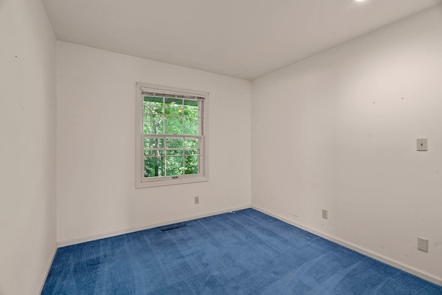 unfurnished room with visible vents, baseboards, and dark colored carpet