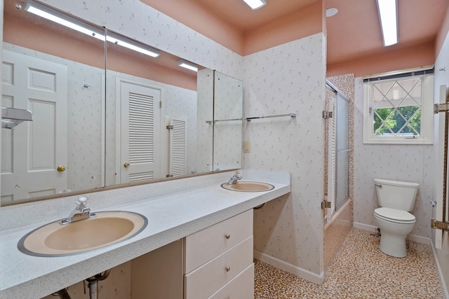 bathroom featuring baseboards, a sink, toilet, and wallpapered walls