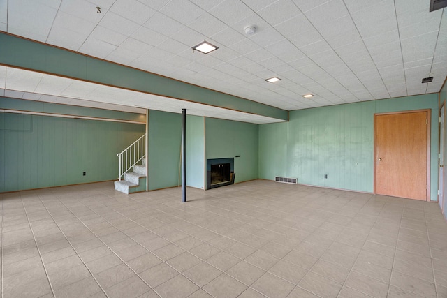 finished basement featuring stairway, a fireplace, and visible vents