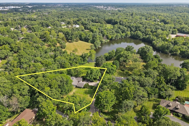 birds eye view of property featuring a water view and a wooded view