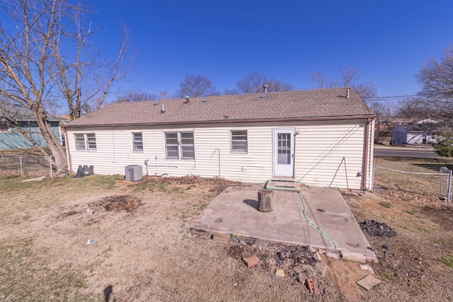 rear view of property featuring a patio, central AC unit, fence, and a shingled roof