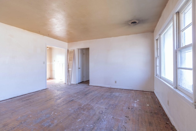 spare room with hardwood / wood-style flooring, baseboards, and visible vents