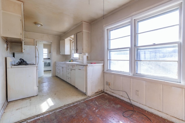 kitchen featuring stove, light countertops, white dishwasher, and a sink