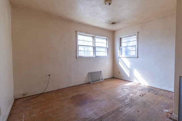 spare room featuring visible vents, baseboards, and wood-type flooring