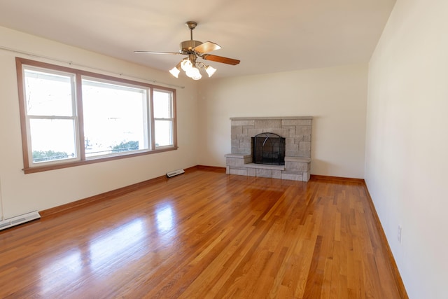 unfurnished living room with baseboards, a stone fireplace, ceiling fan, and light wood finished floors