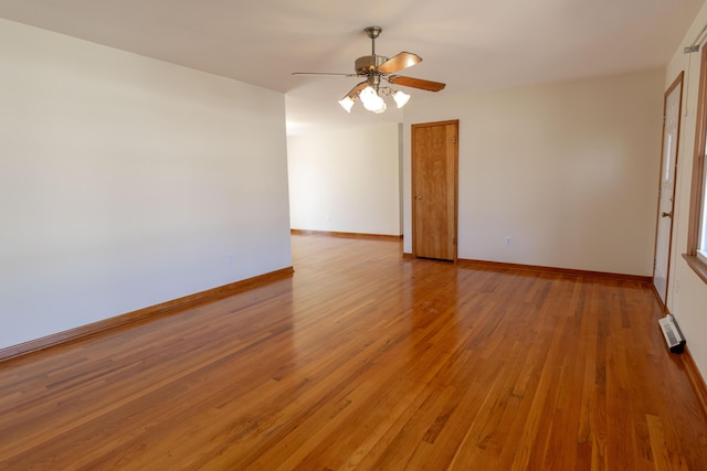 spare room with baseboards, light wood-style floors, and ceiling fan