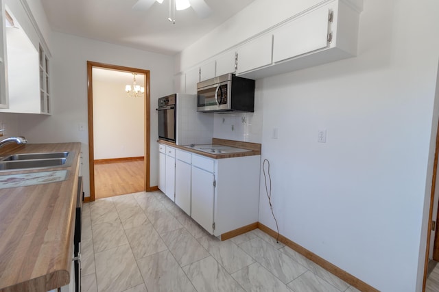 kitchen featuring a sink, decorative backsplash, white cabinetry, stainless steel microwave, and black oven