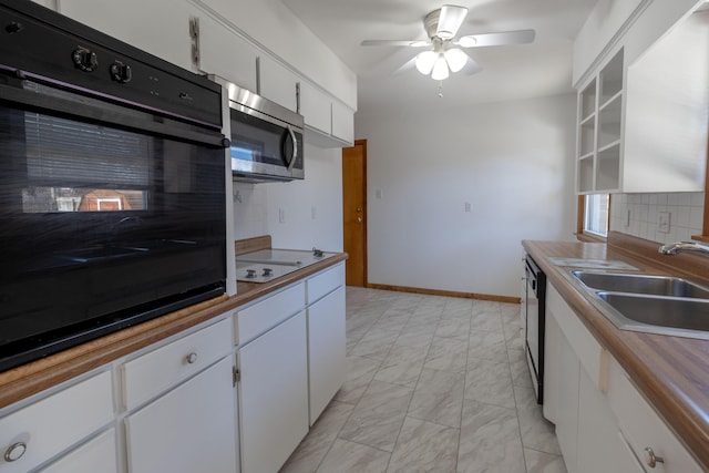 kitchen featuring a sink, black appliances, white cabinets, marble finish floor, and backsplash