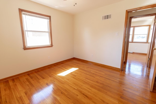 empty room featuring visible vents, baseboards, ceiling fan, and light wood finished floors