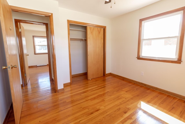 unfurnished bedroom with light wood-style flooring, baseboards, and a closet