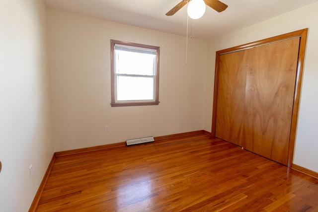 unfurnished bedroom with wood finished floors, visible vents, a closet, and baseboards