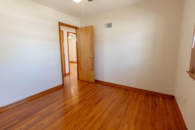 empty room with light wood-style floors, visible vents, and baseboards