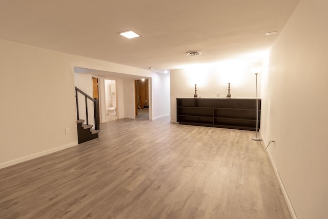 finished basement with visible vents, stairway, baseboards, and wood finished floors