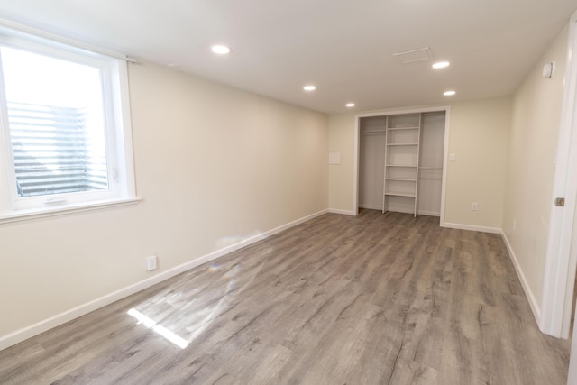 unfurnished bedroom with a closet, recessed lighting, light wood-style flooring, and baseboards