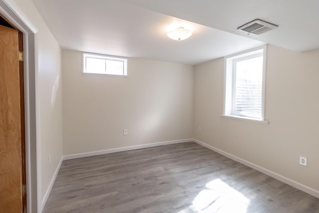 below grade area featuring wood finished floors, visible vents, and baseboards