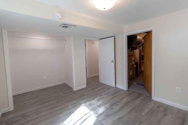 unfurnished bedroom with wood finished floors, visible vents, baseboards, a closet, and a walk in closet