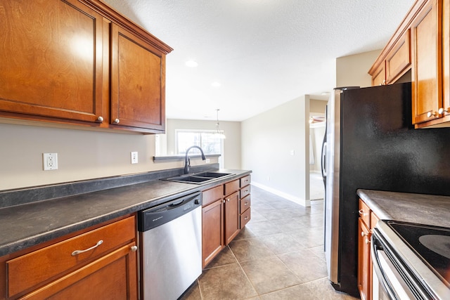 kitchen with a sink, stainless steel dishwasher, dark countertops, brown cabinets, and tile patterned floors