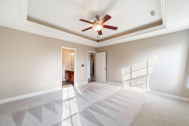 unfurnished bedroom with light carpet, visible vents, a raised ceiling, and baseboards