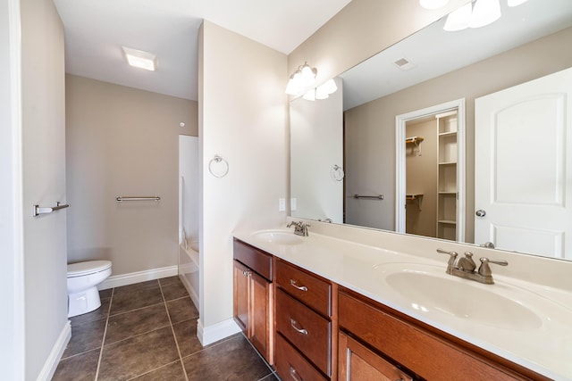 bathroom with tile patterned floors, toilet, double vanity, and a sink