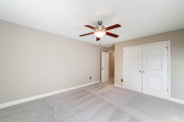 unfurnished bedroom featuring light colored carpet, baseboards, visible vents, and a closet