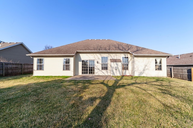 back of property featuring a fenced backyard, a yard, and roof with shingles