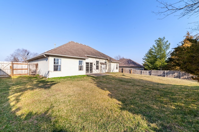 rear view of house featuring a lawn, a patio, a fenced backyard, and roof with shingles