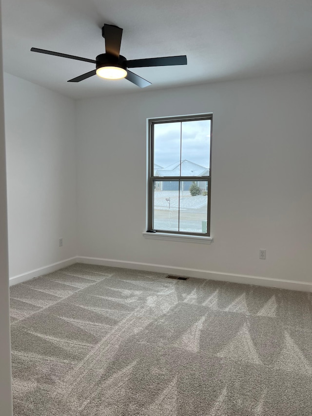 carpeted empty room featuring ceiling fan, visible vents, and baseboards