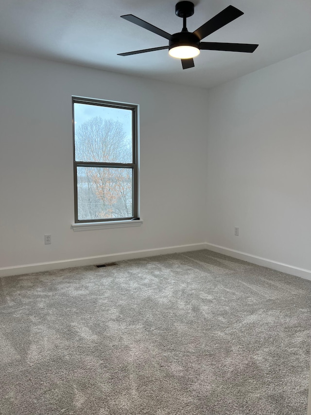 carpeted empty room with visible vents, ceiling fan, and baseboards