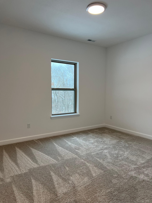 carpeted spare room with visible vents and baseboards