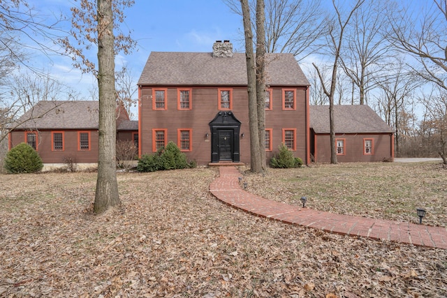 colonial house with a chimney and a shingled roof