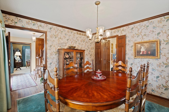 dining area with visible vents, a notable chandelier, wood-type flooring, wallpapered walls, and baseboards