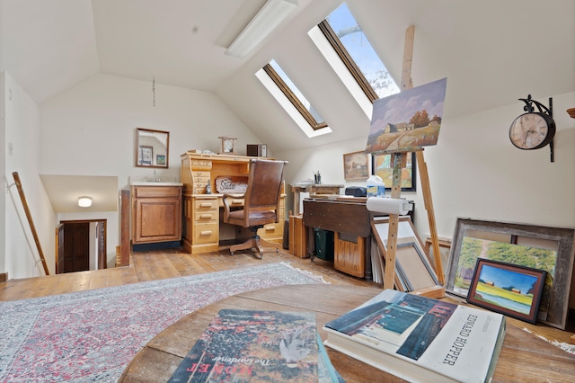 office space with vaulted ceiling with skylight and light wood-style floors